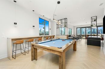 a pool table in a living room with a bar and views of the city at Inspire West Town, CHICAGO, IL, 60642